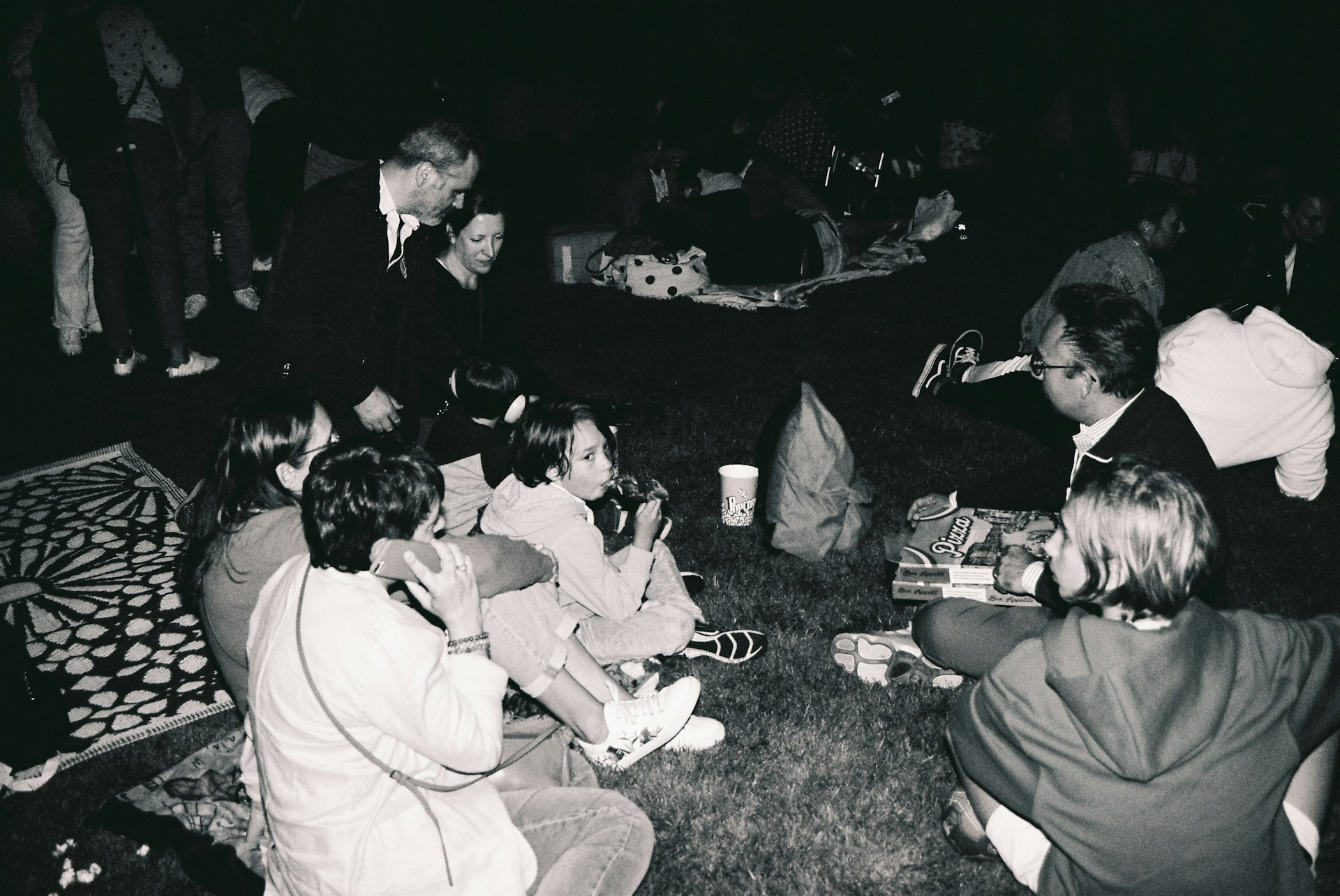 a group of people sitting on the ground eating food